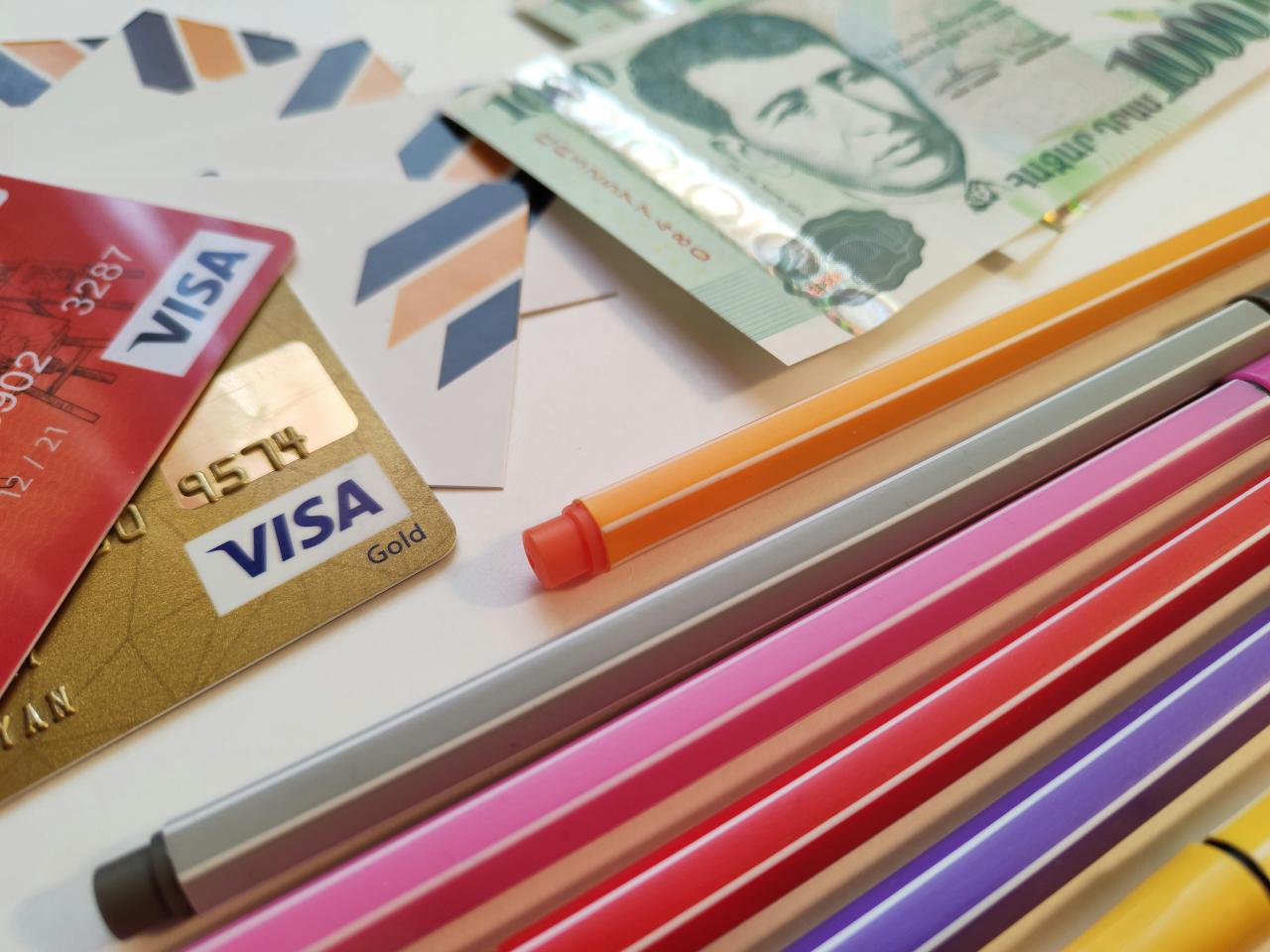 a pile of different colored pencils next to a credit card